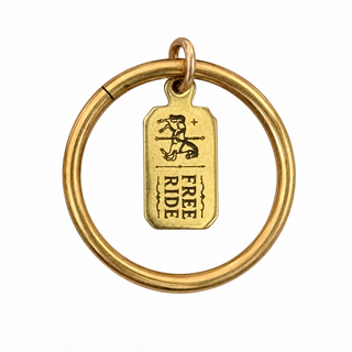 A brass ring with a hanging ticket charm engraved with a flying horses carousel horse   and the words 'FREE RIDE' on a plain white background.
