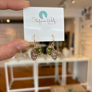 Grape fruit Earrings on a display card held by a hand with a blurred indoor background