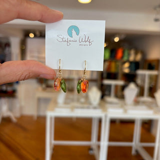 Earrings on a card held by a hand with a blurred indoor background