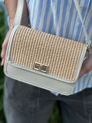 Person holding a woven handbag with off white leather
