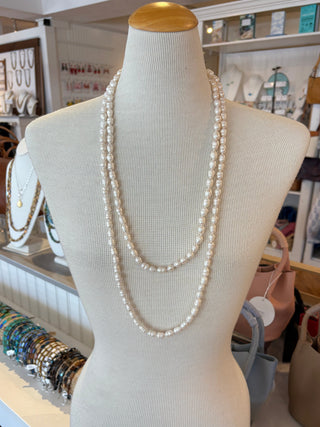 Mannequin torso with long white pearl necklace in a store setting