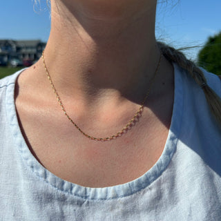 Mini delicate gold paperclip chain necklace on a woman outside
