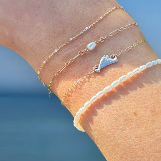 Wrist with permanent bracelets including martha's vineyard charm and pearl charm