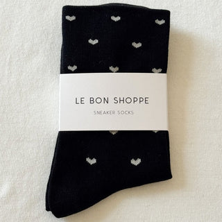 Black socks with heart patterns and a visible label on a light background