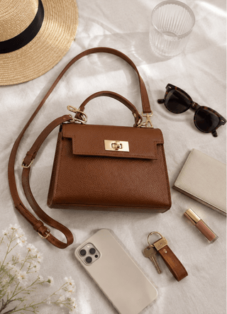 Brown handbag with accessories on a light surface