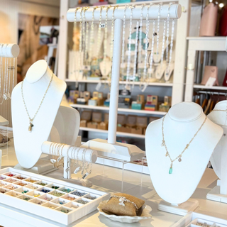 Jewelry store display with necklaces on mannequins and a table with jewelry items.