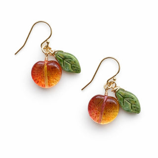 Pair of 14k gold fill earrings with fruit shaped peaches and green leaves on white background