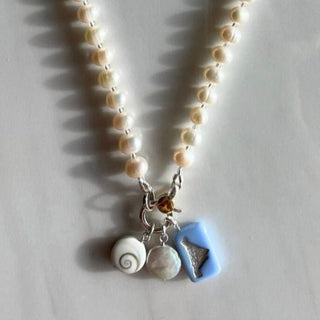 pearl charm necklace with charms on marble background 