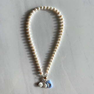 pearl charm necklace with charms on marble background 