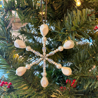 mother of pearl, shell, and pearl snowflake handmade beaded ornament on a decorate christmas tree 