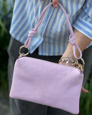 Person holding a pink handbag with a matching handle.