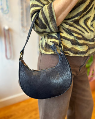 Person wearing a black leather handbag with a zebra-patterned sweater and brown pants.