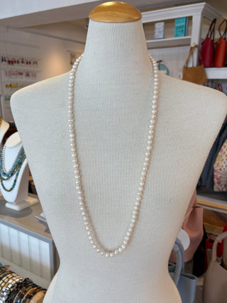 Mannequin torso with a long knotted freshwater pearl necklace  in a store setting
