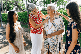 4 Multigenerational Women Adorning Each Other with Chunky Pearl Jewelry as a Family